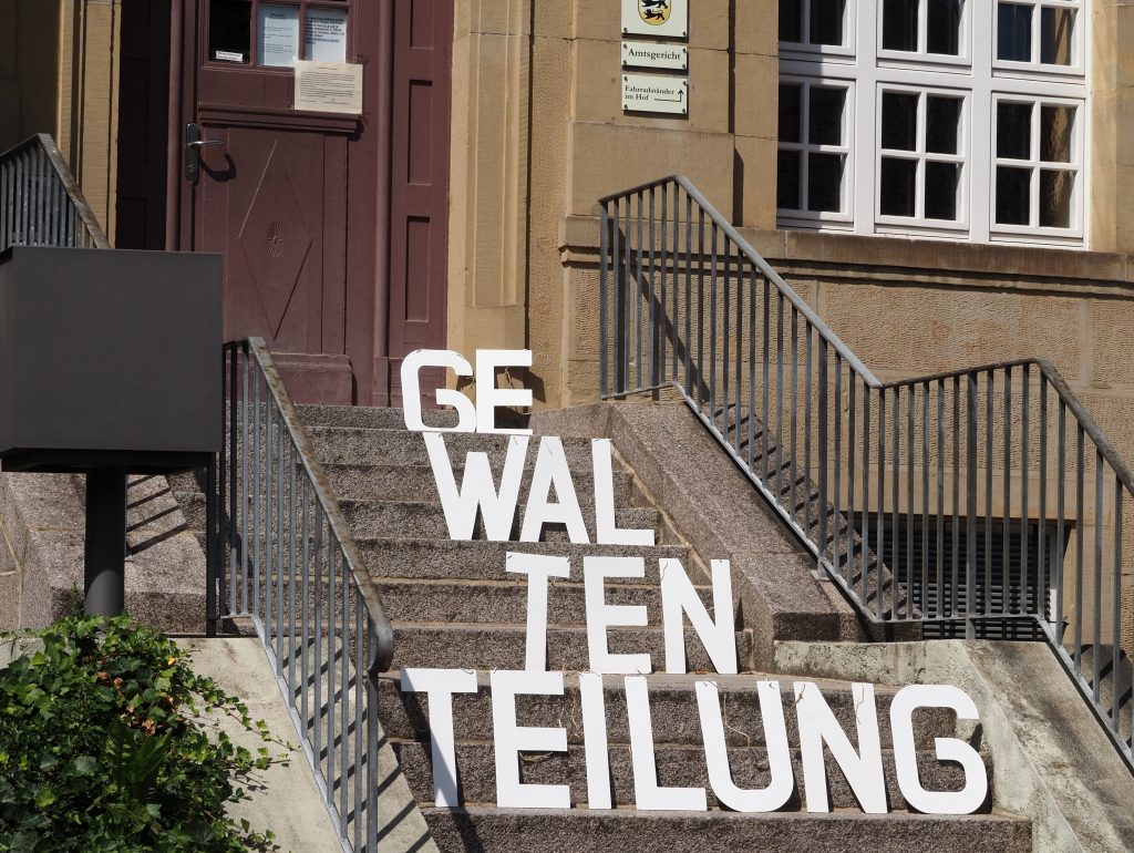 Der Begriff Gewaltenteilung dargestellt in Holzbuchstaben auf der Treppe des Wieslocher Amtsgerichts