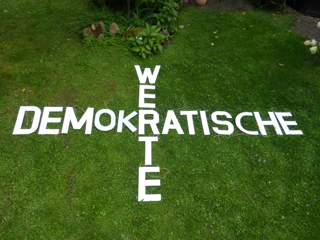 Die Begriffe Demokratische Werte dargestellt mit Holzbuchstaben im Gras liegend