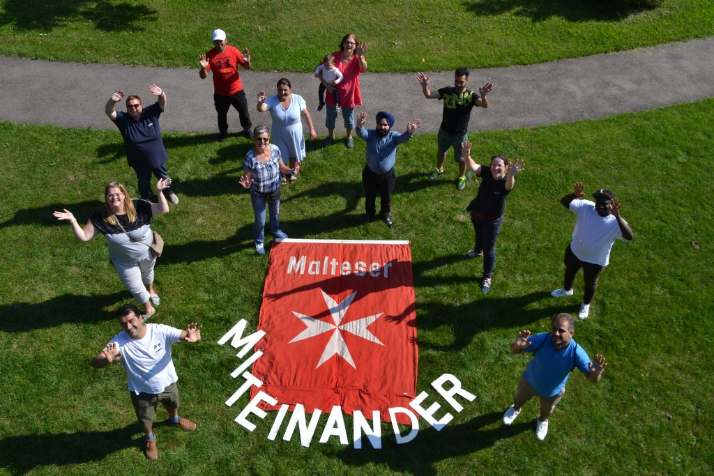 Die Malteser stellen den Begriff "Miteinander" in Holzbuchstaben dar